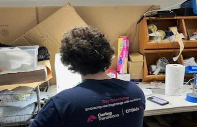 Team member sorting and organizing clothing and household items during a senior downsizing project for an online estate auction.